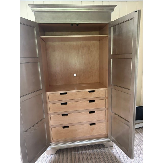 A striking Regency-style armoire by Nancy Corzine, finished in a luminous tea leaf silver that gives the piece a soft,...