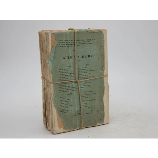 A bundle of two vintage Victor Hugo books in French. Tied together with a decorative rope trim. Binding has come loose.