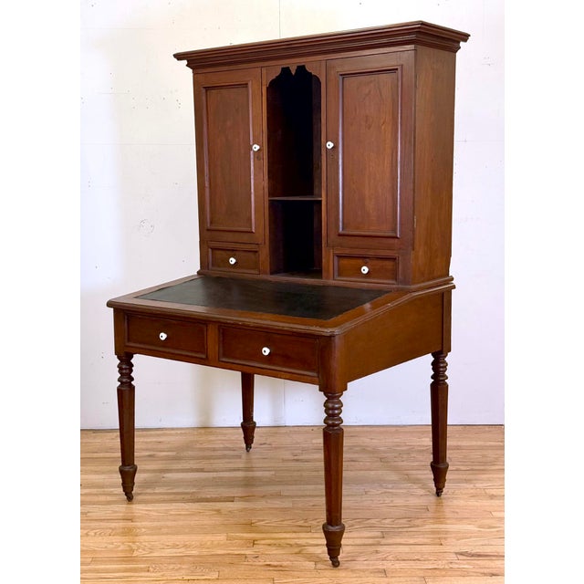 Federal style postmaster's secretary desk made of dark stained walnut. The top section features a double cabinet with two...
