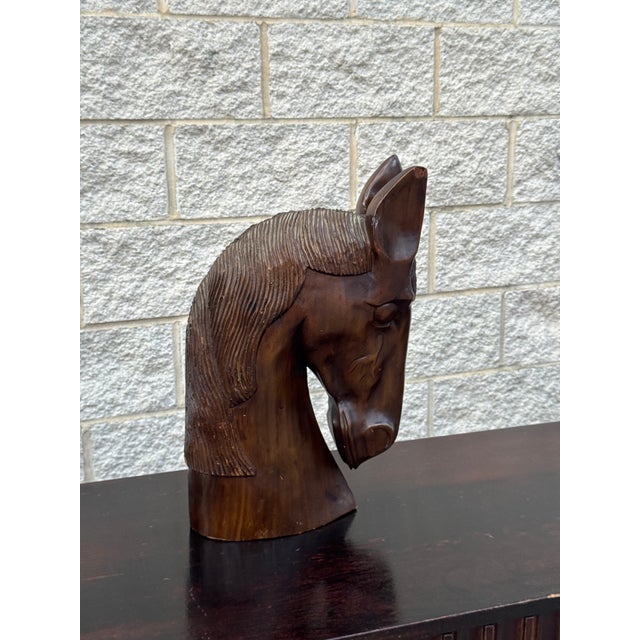 Large hand-carved wood horse head sculpture with detailed carved mane and expressive features. The elongated form and warm...