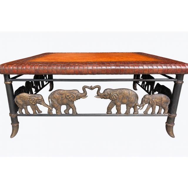 Maitland-Smith figural coffee table featuring a warm tan hand-tooled leather top with a woven leather border, set on a...