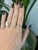 A 0.40-carat padparadscha sapphire oval sits at the centre of this solid 14K white gold ring, framed by eighteen earth-...