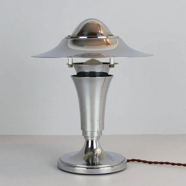 This table lamp is made of chromed metal. The lamp holds a B22 socket and the wiring has been checked. Labeled with...