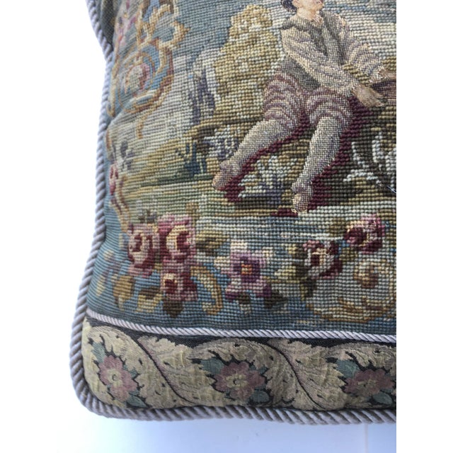 This antique needlepoint pillow features petite point figures. The insert pillow is filled with down & feathers The...