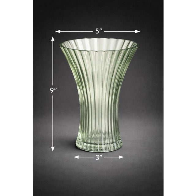 A beautifully sculpted vintage green glass vase featuring a fluted, ribbed form and softly scalloped rim. Part of our...