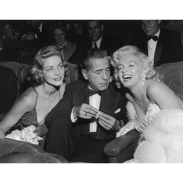 Married couple Humphrey Bogart and Lauren Bacall share a joke with Marilyn Monroe at a film screening. 16" x 20" print...