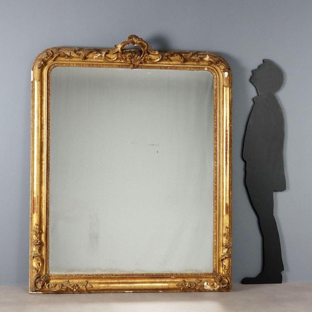 Gilded wood mirror, shaped frame embellished with floral, leaf, and scroll carvings in pastiglia. Mercury mirror, missing...