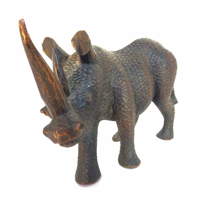 This hand-carved wooden table-top sculpture of a black rhinoceros is chip-carved in a realistic manner with understanding...