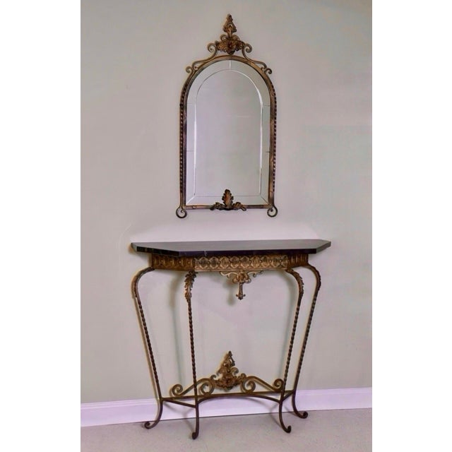Oscar Bach attributed gilded iron console with a black marble top and arched, beveled mirror, circa 1920. A gorgeous set...