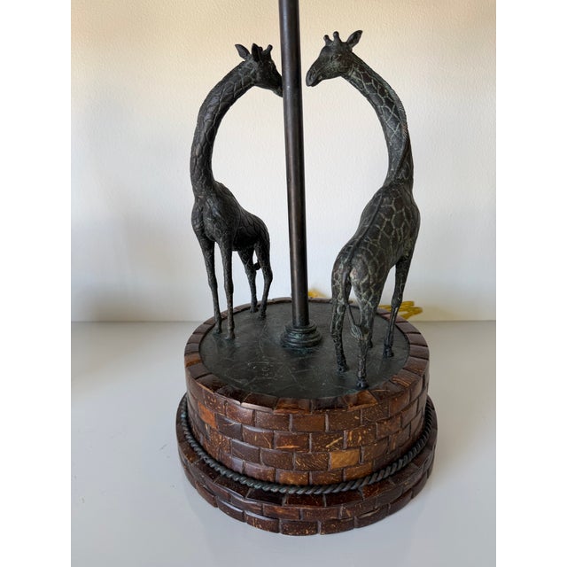 Striking and sculptural pair of vintage Maitland-Smith table lamps featuring elegant bronze giraffes gracefully encircling...
