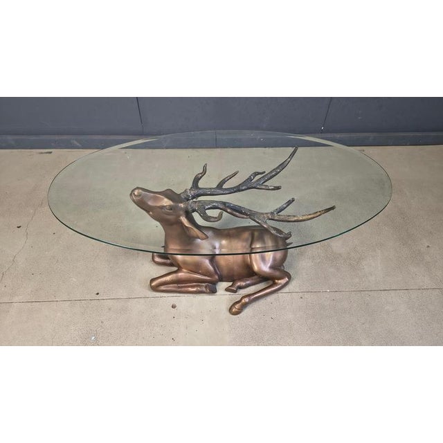 Impressive coffee table feauturing a beautiful brass deer/stag sculpture with an oval beveled glass top. The deer is set...