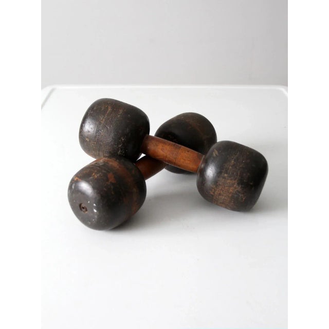 This is a pair of antique wooden dumbbells. The 19th century wood hand weights feature exaggerated black toned end...
