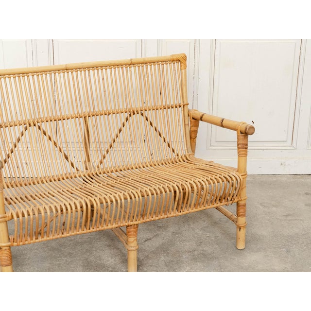 A 1970s bamboo and rattan bench, remarkable for its intricate weaving. The slender rattan rods create a play of vertical...