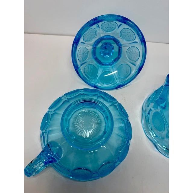 A striking two-piece set of vintage Fostoria Coin Glass in brilliant light blue press glass. First introduced by Fostoria...