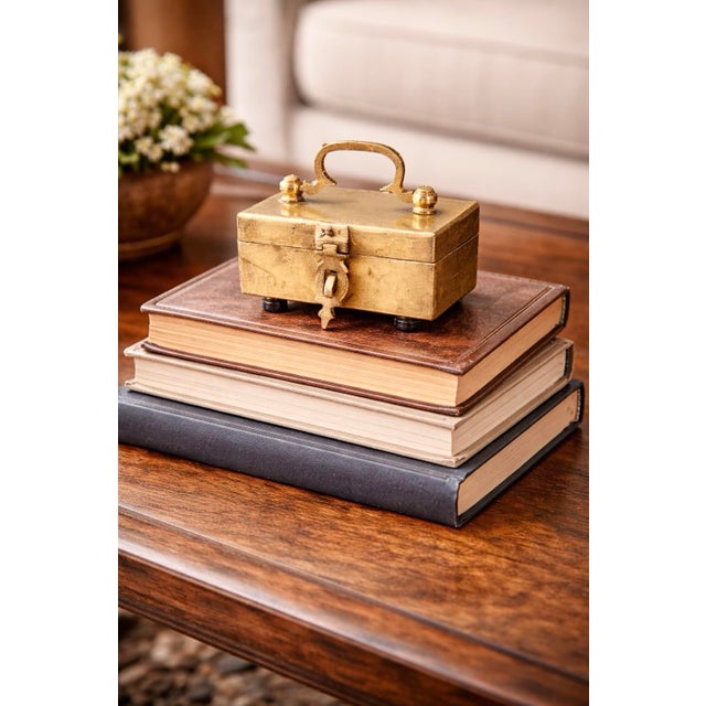A charming vintage brass locking box featuring a compact rectangular form, integrated top handle, and working clasp with...