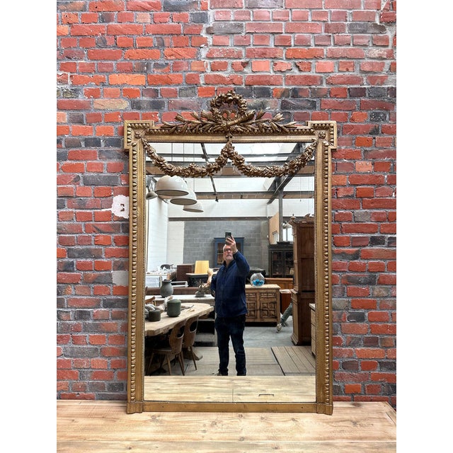 Huge Louis XVI-style gilded mirror. This magnificent piece is adorned with a richly decorated bouquet and garlands...