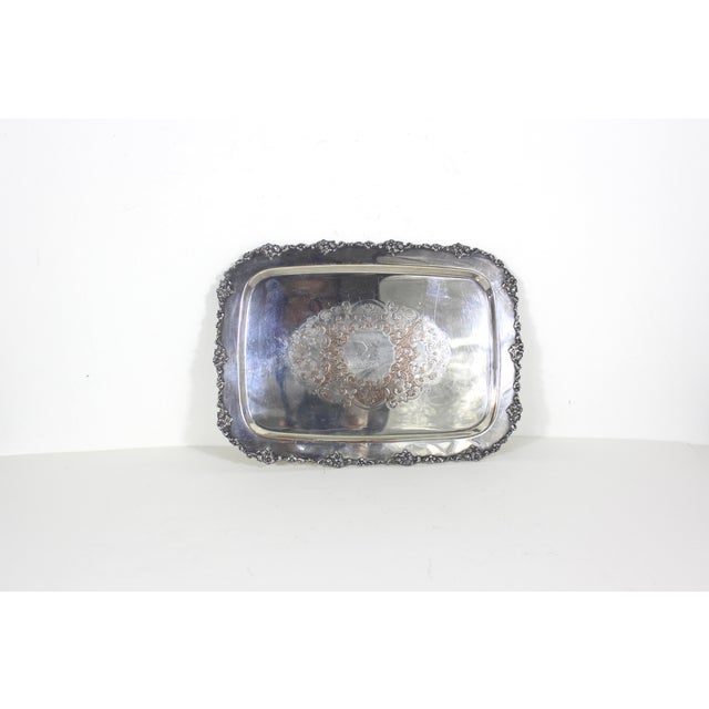 Small, rectangular vintage silver plated tray with raised floral detail around the edge and an embossed base. This is in...