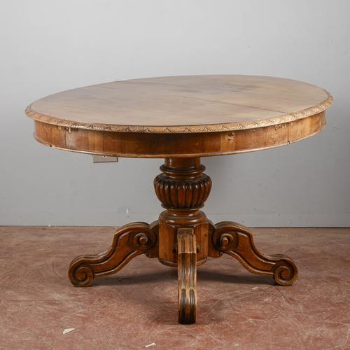 This splendid oval extendable table, veneered in walnut with a carved central leg and crafted from solid walnut, is an...