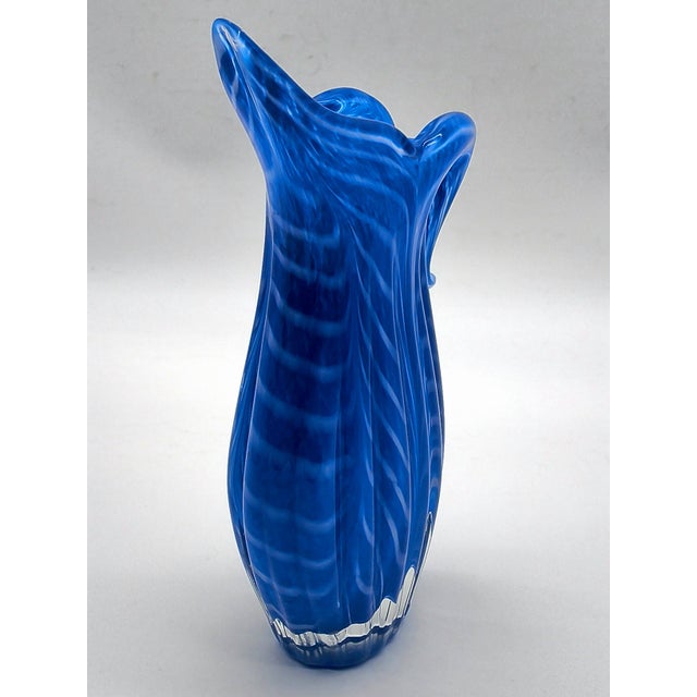 Vibrant Cobalt blue art glass pitcher vase featuring a delicate white feathered swirl pattern and a clear glass base. This...