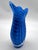 Vibrant Cobalt blue art glass pitcher vase featuring a delicate white feathered swirl pattern and a clear glass base. This...