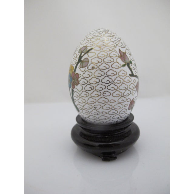 Vintage Chinese Cloisonne metal egg. White background with colorful hand painted enamel bird and lotus flowers amongst...