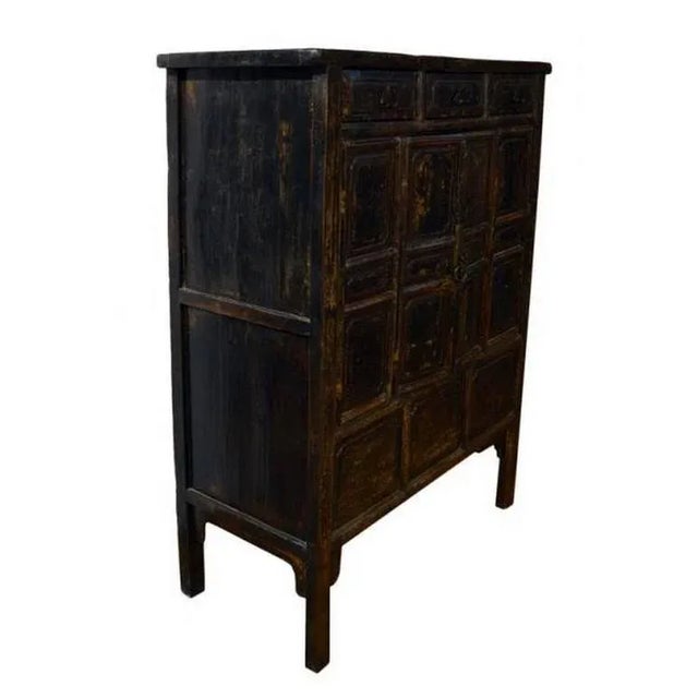 A dark brown lacquered Chinese cabinet from the early 19th century. This hand carved Chinese cabinet features 18 panels on...