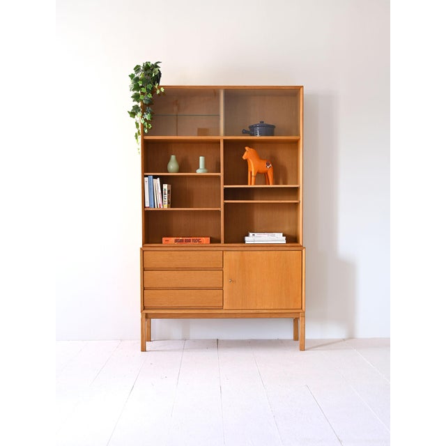 Vintage bookcase made up of two modules, the lower part is a small sideboard with door and drawers, while the upper part...