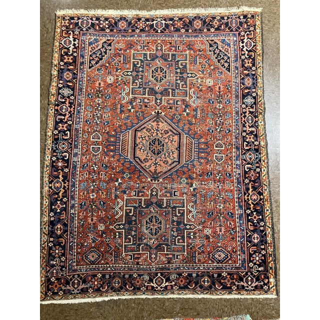 Hand-knotted Persian Garadjeh Heriz wool rug with a rust-red field and bold geometric medallion design in navy and ivory....