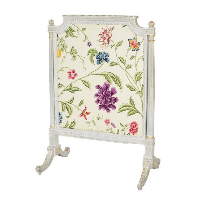 A French Louis XVI style fire screen offers white painted cared wood frame with gilt highlights and floral fabric, 20th...