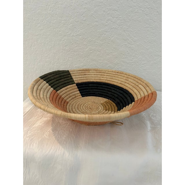 Stylish vintage African coil basket in earthtone shades. Generous size. Loop on back should desire to display hanging.