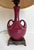 Here is a beautiful, vintage ceramic table lamp, likely dating to the 1960s, finished in a rich burgundy glaze that gives...