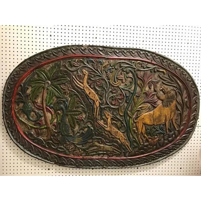 Carved wood plaque depicting animals. Having exotic animals including birds, lions and gazelles.