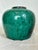 This beautiful Chinese pottery oil jar is green with black on one side.