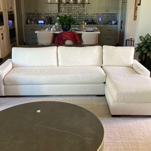 This Restoration Hardware sectional features a clean, modern design with a right-facing chaise. The soft beige upholstery...