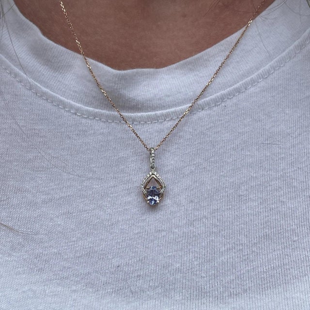A tanzanite glows with blue brilliance at the heart of this oval pendant, framed by a trail of brilliant natural diamonds....