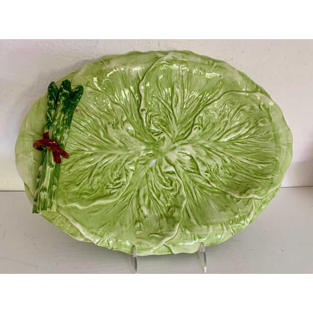 An Italian majolica cabbage leaf platter adorned with an asparagus bunch tied in a red ribbon on the side. Very detailed...
