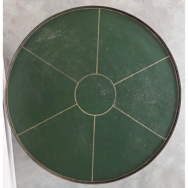 Handsome mid-century round green leather top mahogany coffee table with fluted legs. The table features a classic period...