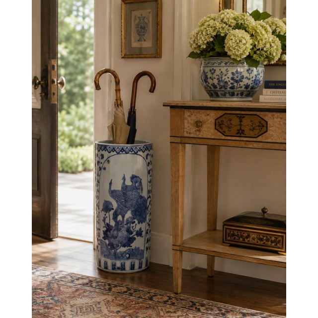 A classic blue and white porcelain umbrella stand in the chinoiserie tradition, featuring finely rendered birds among...