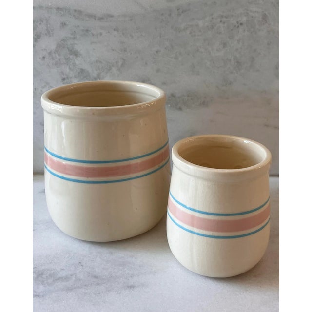 Set of 2 vintage McCoy ceramic canisters with cream glaze and pink and blue stripes. No lids. Large canister "133"...