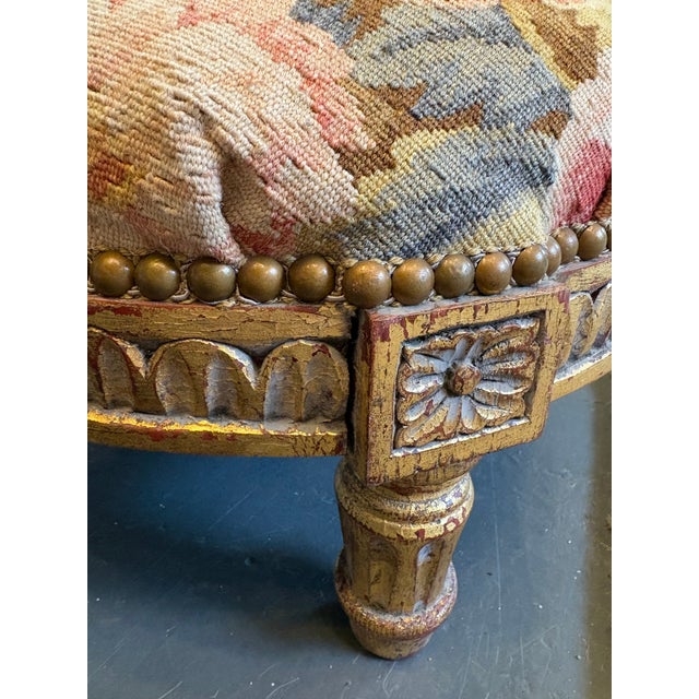 This is an antique footstool with a floral tapestry. It has Giltwood engraved wood and a spectacular floral design...