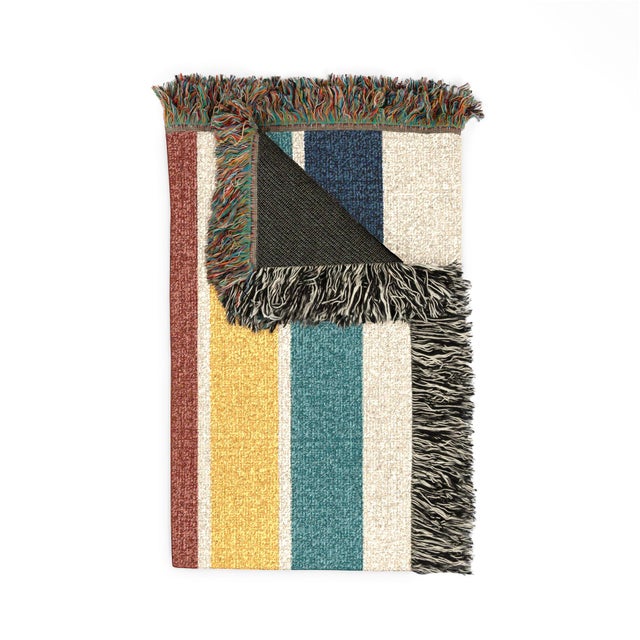 This mid-century modern geometric woven throw blanket features elongated blocks of teal, mustard yellow, rust, and navy on...