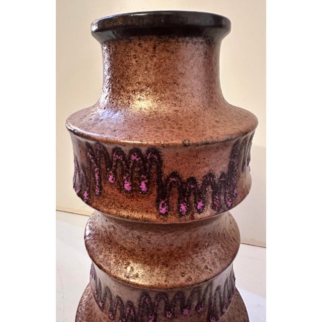 A tiered, sculptural vase rising in bold stacked bands, each ring catching light differently against a warm, mottled...