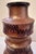 A tiered, sculptural vase rising in bold stacked bands, each ring catching light differently against a warm, mottled...
