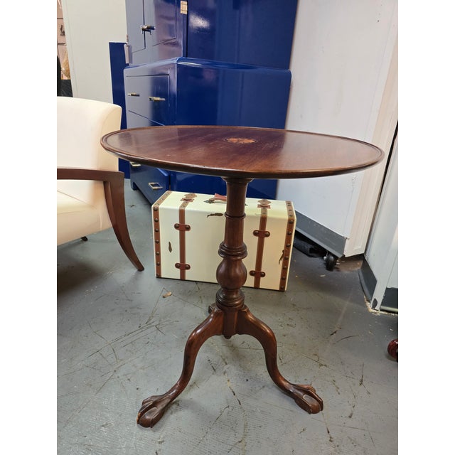 Elegant Chippendale style mahogany tilt top tea table. This round table features an inlay top.
