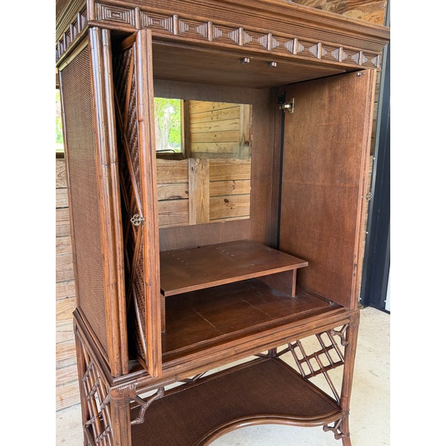 A striking vintage rattan cabinet featuring a sculptural pagoda top and intricate fretwork doors over woven rattan panels....