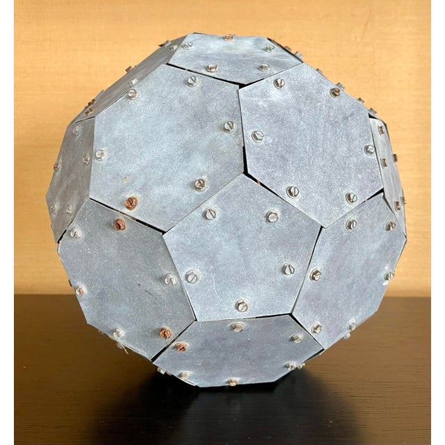 A striking 32-sided geometric sculpture hand-assembled from individually cut steel panels and secured with exposed rivets,...