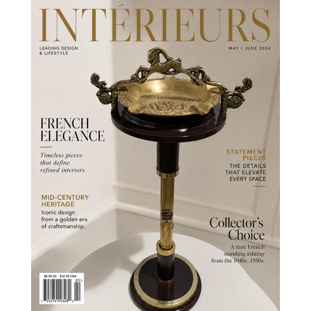 This standing ashtray features a polished brass bowl and ornate bronze-finished handles mounted atop a dark fluted metal...
