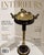 This standing ashtray features a polished brass bowl and ornate bronze-finished handles mounted atop a dark fluted metal...