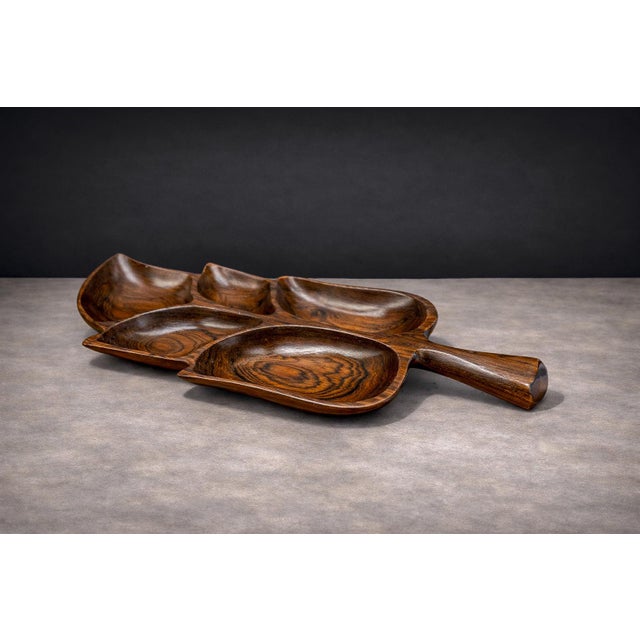 Carved from a single block of richly figured hardwood, this sculptural serving platter evokes the organic contour of a...