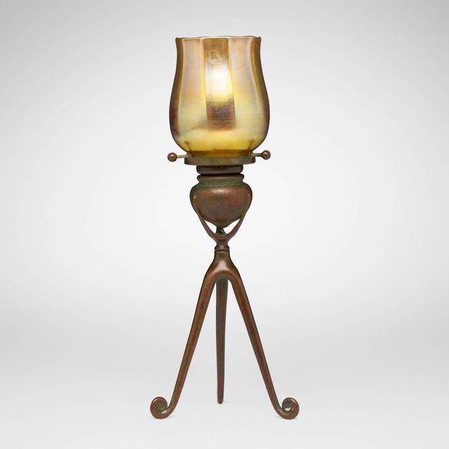 This exceptional Tiffany Studios Tripod candlestick with Favrile glass shade was created in the United States by Tiffany...